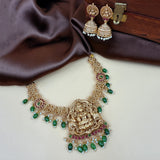 Gold necklace with green and red stones on a brown fabric background