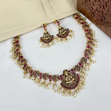 Gold necklace with red stones and matching earrings on a white surface