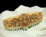 Ornate gold necklace with green beads on a white fabric background