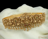 Gold jewelry belt with intricate designs on a white fabric background