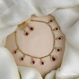 Gold necklace with red gemstones on a white fabric background, featuring the brand 'Jewel Palace'.