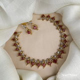 Jewelry set with necklace, bracelet, and earrings on a beige stand with a white fabric background.