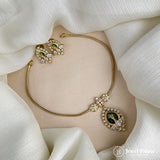 Gold jewelry set with green gemstones on a white fabric background