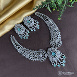 Silver necklace with turquoise stones on a dark surface with green leaves