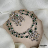 Silver necklace with green gemstones on a white fabric background