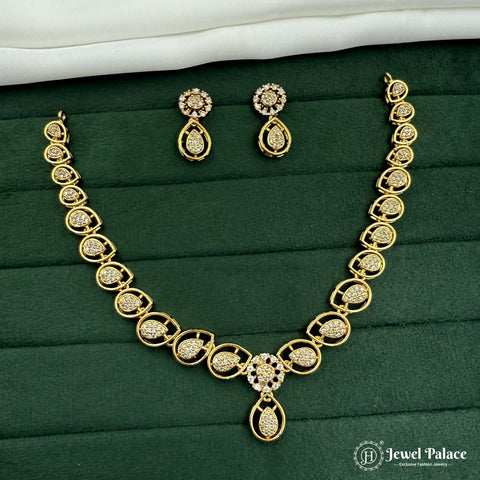 Gold necklace and earrings set on a green fabric background with 'Jewel Palace' branding.