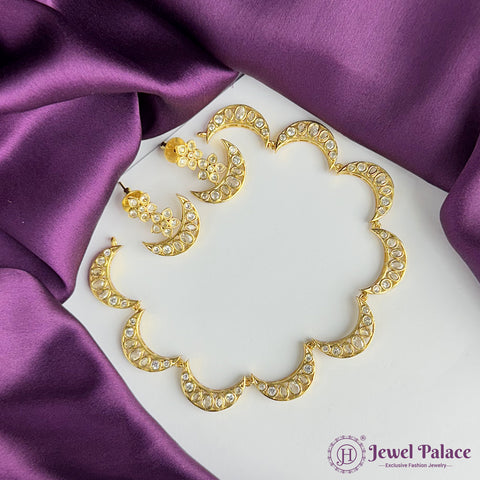 Gold necklace and earrings on a white stand with purple fabric background, Jewel Palace brand visible.