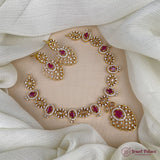 Gold necklace with red gemstones on a white fabric background, brand 'Jewel Palace' visible.