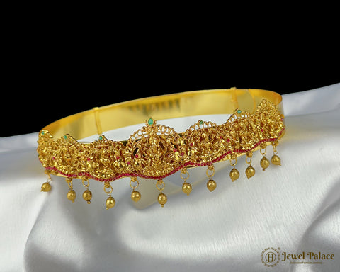 Gold necklace with red accents on a white fabric background