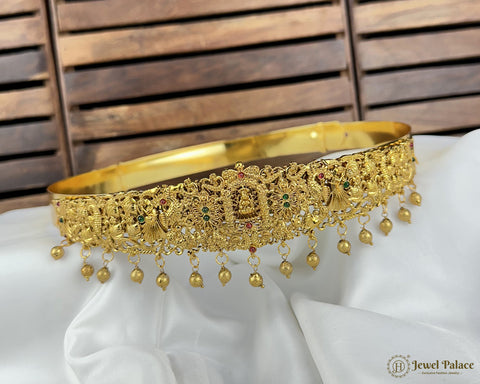 Gold necklace with intricate designs and beads on a white fabric background