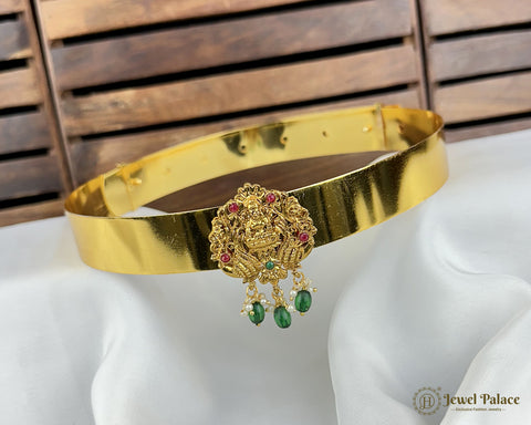 Gold belt with decorative clasp on a mannequin against a wooden background