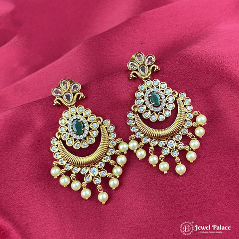 Gold earrings with pearls and gemstones on a pink fabric background, featuring the brand 'Jewel Palace'.