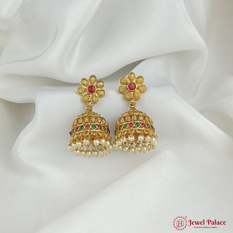 Gold earrings with pearls and gemstones on a white fabric background, featuring the Jewel Palace logo.