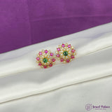 Pair of gold earrings with pink and green gemstones on a white surface with purple background