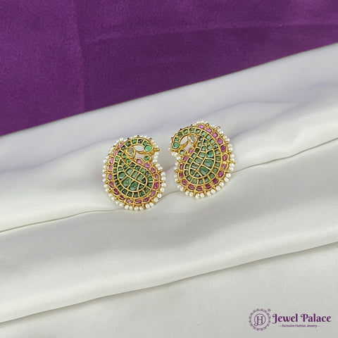 Ornate earrings with green and pink stones on a white fabric background, brand 'Jewel Palace' visible.