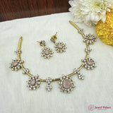 Jewelry set with necklace and earrings on a white fabric background with flowers.