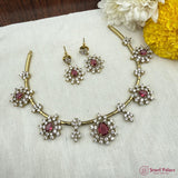 Jewelry set with necklace and earrings on a textured surface with flowers.