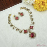 Jewelry set with red gemstones on a white fabric background with flowers.