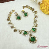 Necklace and earrings set with green gemstones on a white fabric background