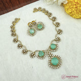 Jewelry set with necklace and earrings on a textured surface with flowers.