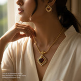Woman wearing a gold necklace and earrings with a blurred background