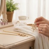 Person adjusting a decorative brooch on a white garment with a blurred indoor setting.
