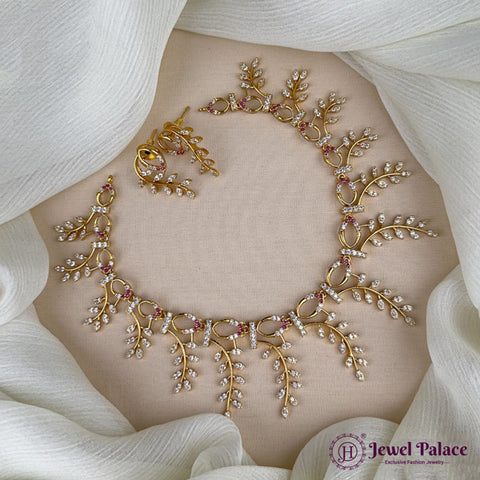 Gold necklace with floral design on a white fabric background, featuring 'Jewel Palace' branding.