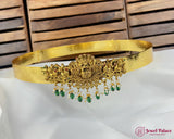 Gold headband with green gemstones on a white cushion with wooden background