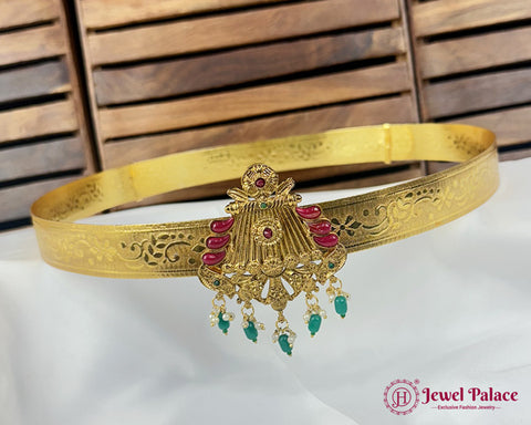 Gold belt with jewelry design on a white surface with wooden background