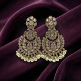 A pair of ornate gold-toned chandelier earrings with clear stones and white pearl fringe, displayed on draped deep purple velvet fabric.