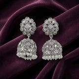 A pair of silver-toned Indian jhumka earrings with clear teardrop stones and pearl bead fringe, displayed on a draped deep purple velvet fabric.