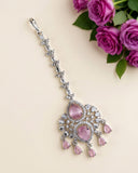 A silver-toned choker necklace with a long, ornate pendant featuring pink teardrop gemstones and clear crystals, styled on a beige background with pink roses in the corner.