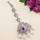 A silver-toned traditional Indian choker necklace with a central purple gemstone and dangling white pearls, styled on a beige background with pink roses in the corner.