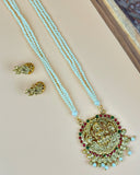 Gold necklace with blue beads and a decorative pendant on a beige surface.