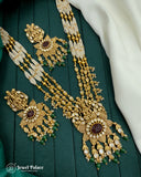 Gold necklace with green stones on a green fabric background, brand 'Jewel Palace' visible.