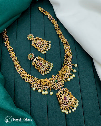 Gold necklace with pearl and gemstone details on a green fabric background, brand 'Jewel Palace' visible.