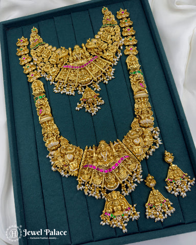 Ornate gold necklace with green and red stones on a teal background, brand 'Jewel Palace' visible.