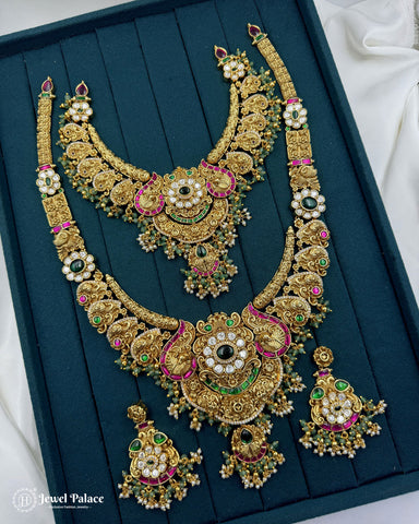 Ornate gold necklace with green and red stones on a teal background, brand 'Jewel Palace' visible.
