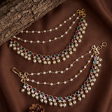 Gold-plated double-layered waist chains decorated with white faux pearls and green and red gemstone clusters, displayed on a brown fabric background with a wood slice prop.