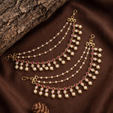 Gold-toned chain waist chains decorated with white faux pearls and pink gemstone accents, arranged on a brown fabric background with a tree branch and pinecone prop.