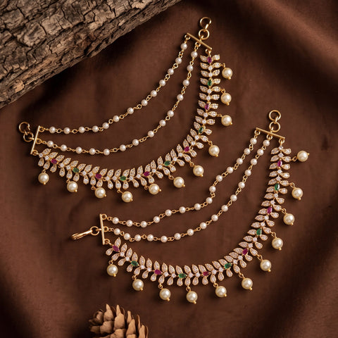 Gold-toned Indian choker necklace with white faux pearls and small green and red gemstone accents, displayed on a brown satin fabric background with a piece of wood.