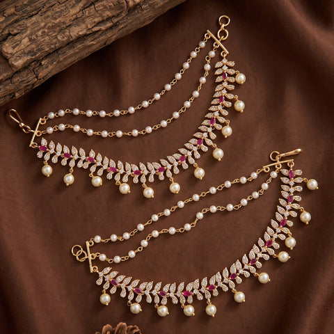 A pair of gold-toned Indian maang tikka headchains decorated with white faux pearls and small pink gemstone accents, displayed on a brown satin fabric background.
