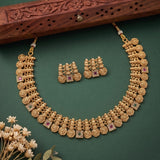 Gold-toned traditional Indian jewelry set featuring a multi-strand necklace with floral and square stone details, matching stud earrings, and a carved wooden prop on a dark green background.