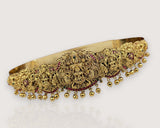 Gold necklace with intricate designs and red stones on a white background
