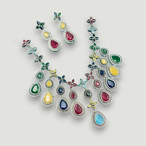 Multicolored gemstone necklace and earrings on a light gray background