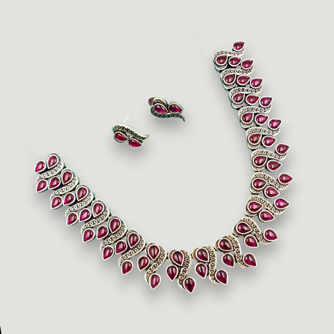 Necklace and earrings with red gemstones on a light gray background