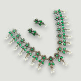Jewelry set with green gemstones on a light gray background