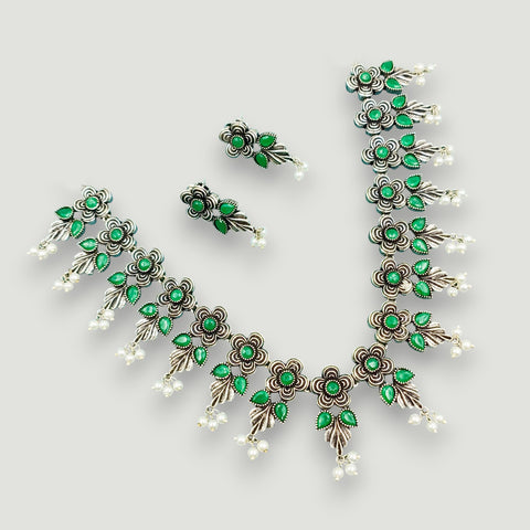 Jewelry set with green gemstones on a light gray background