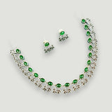 Jewelry set with necklace and earrings featuring green stones on a light gray background