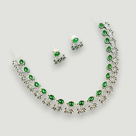 Jewelry set with necklace and earrings featuring green stones on a light gray background